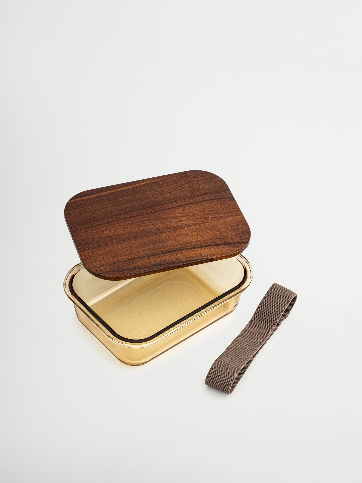 Stilvoll organisiert aufbewahren mit Tamar, hergestellt aus bernsteinfarbenem Glas und veredelt mit einem Holzdeckel. Funktional und elegant, ideal für bewusstes Aufbewahren, Meal Prep und Ordnung in der Küche. Erhältlich in drei Größen: Die kleinste Größe eignet sich perfekt für Joghurt, Nüsse oder Snacks. Die Glasschale (ohne Deckel) ist ofenfest, sodass Mahlzeiten direkt erwärmt werden können. Ein passendes Gummiband hält den Deckel sicher an Ort und Stelle.