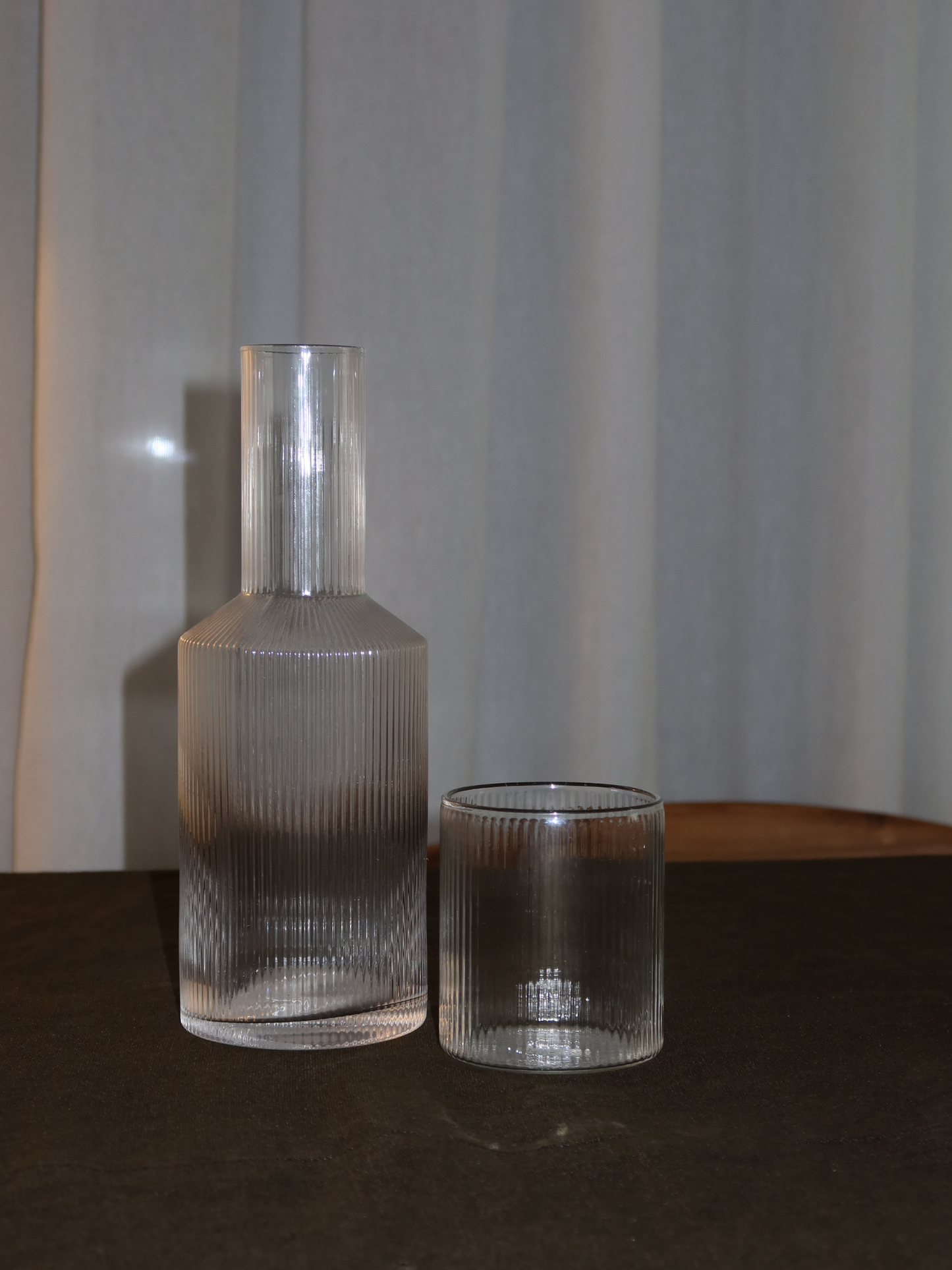 Pour Bottle Neko, an elegant water or juice pitcher with a subtle ribbed texture that beautifully captures light and shadow. Perfect for serving water, juice, or other refreshing drinks in style. Made from durable, clear borosilicate glass—strong and heat-resistant—with a handy shape that makes filling and pouring easy. The ribbed structure adds a unique, playful touch without being overpowering. Pair Neko with matching glasses (sold separately) for a complete and stylish set