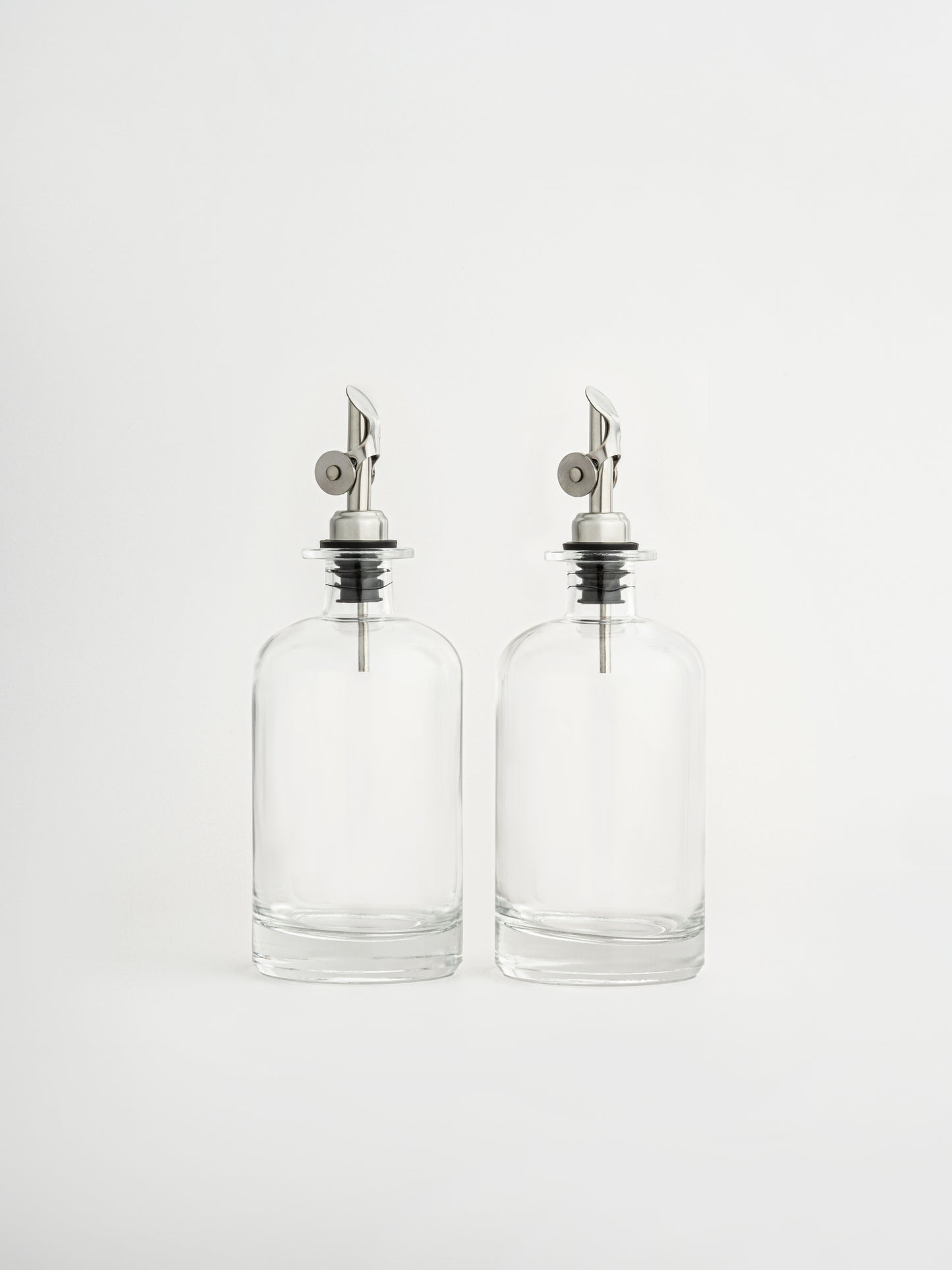 oil dispenser silver cap, vinegar dispenser silver spout, glass oil bottle, glass vinegar bottle, dispenser in two sizes, olive oil bottle, airtight oil container, silver pouring spout, non-drip oil dispenser, kitchen organizer bottle, elegant glass dispenser, modern kitchen accessory, pour control spout, oil and vinegar set, storage bottle for kitchen