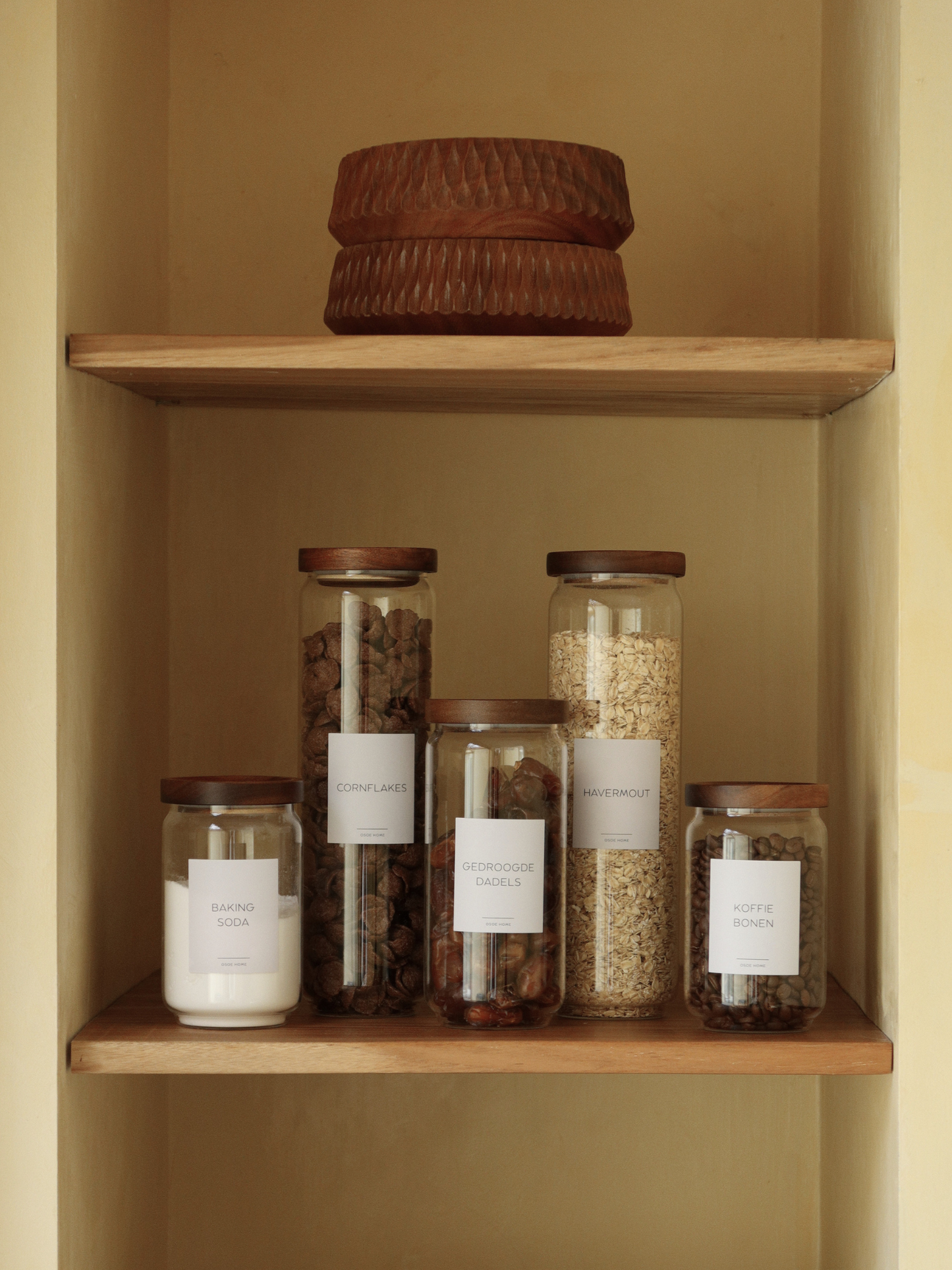 Airtight glass pantry jar Nour with dark brown acacia wood lid for elegant kitchen and pantry organization, made from toxin-free, PFAS-free and BPA-free materials, perfect for storing pasta, rice, coffee, snacks and dry foods in a stylish and organized way, featuring a transparent glass canister design with a thick natural acacia wooden lid and available in four different sizes for modern countertop styling and minimalist kitchen storage.