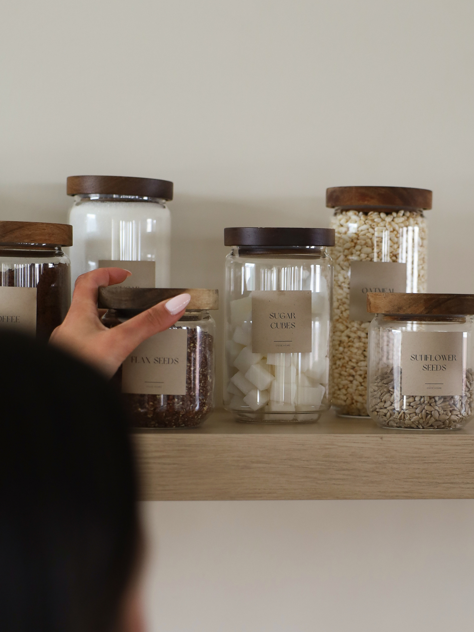 Airtight glass pantry jar Nour with dark brown acacia wood lid for elegant kitchen and pantry organization, made from toxin-free, PFAS-free and BPA-free materials, perfect for storing pasta, rice, coffee, snacks and dry foods in a stylish and organized way, featuring a transparent glass canister design with a thick natural acacia wooden lid and available in four different sizes for modern countertop styling and minimalist kitchen storage.