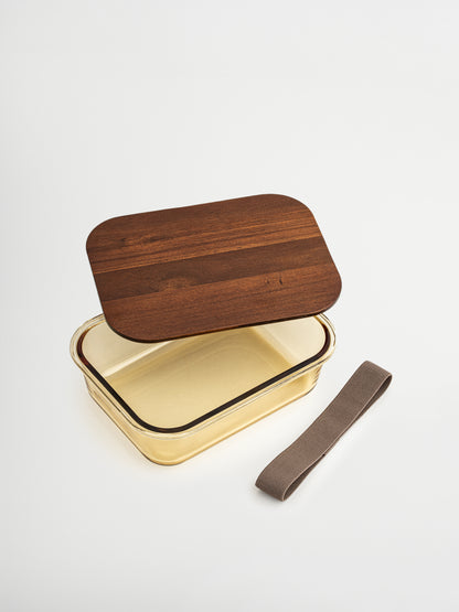 Organize and store in style with Tamar, made from amber-colored glass and finished with a wooden lid. Functional and stylish, perfect for mindful storage, meal prep, and organization. Available in three sizes: the smallest is ideal for yogurt, nuts, or snacks. The glass bowl (without lid) is oven-safe, allowing you to heat meals directly. A matching elastic band keeps the lid securely in place. All food-contact parts are non-toxic and BPA-free.
