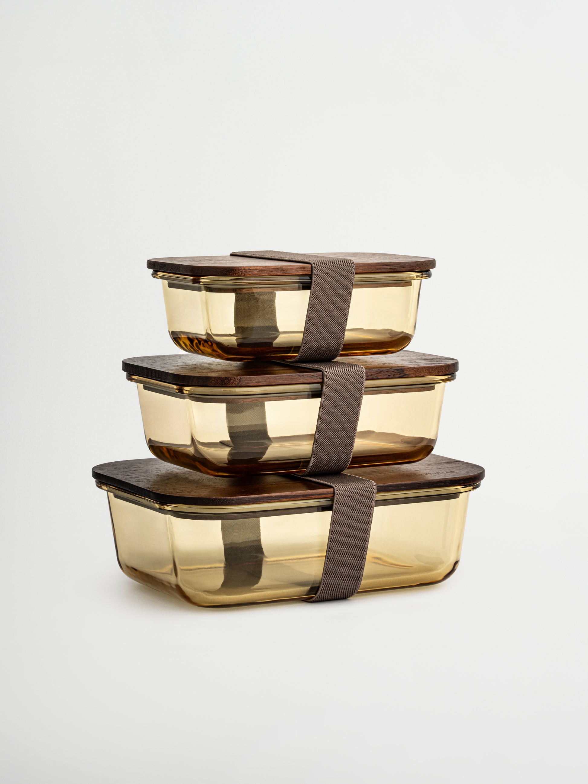 Georganiseerd bewaren in stijl met Tamar, gemaakt van amberkleurig glas en afgewerkt met een houten deksel. Functioneel én stijlvol, ideaal voor wie bewust wil bewaren, opwarmen en organiseren. Verkrijgbaar in drie maten: het kleinste formaat is perfect voor yoghurt, noten of een tussendoortje. De glazen schaal (zonder deksel) is ovenbestendig, waardoor je maaltijden direct opgewarmd kunnen worden. Het bijpassend elastiek houdt het deksel extra goed op zijn plek. Alle onderdelen die met voedsel in aanraking