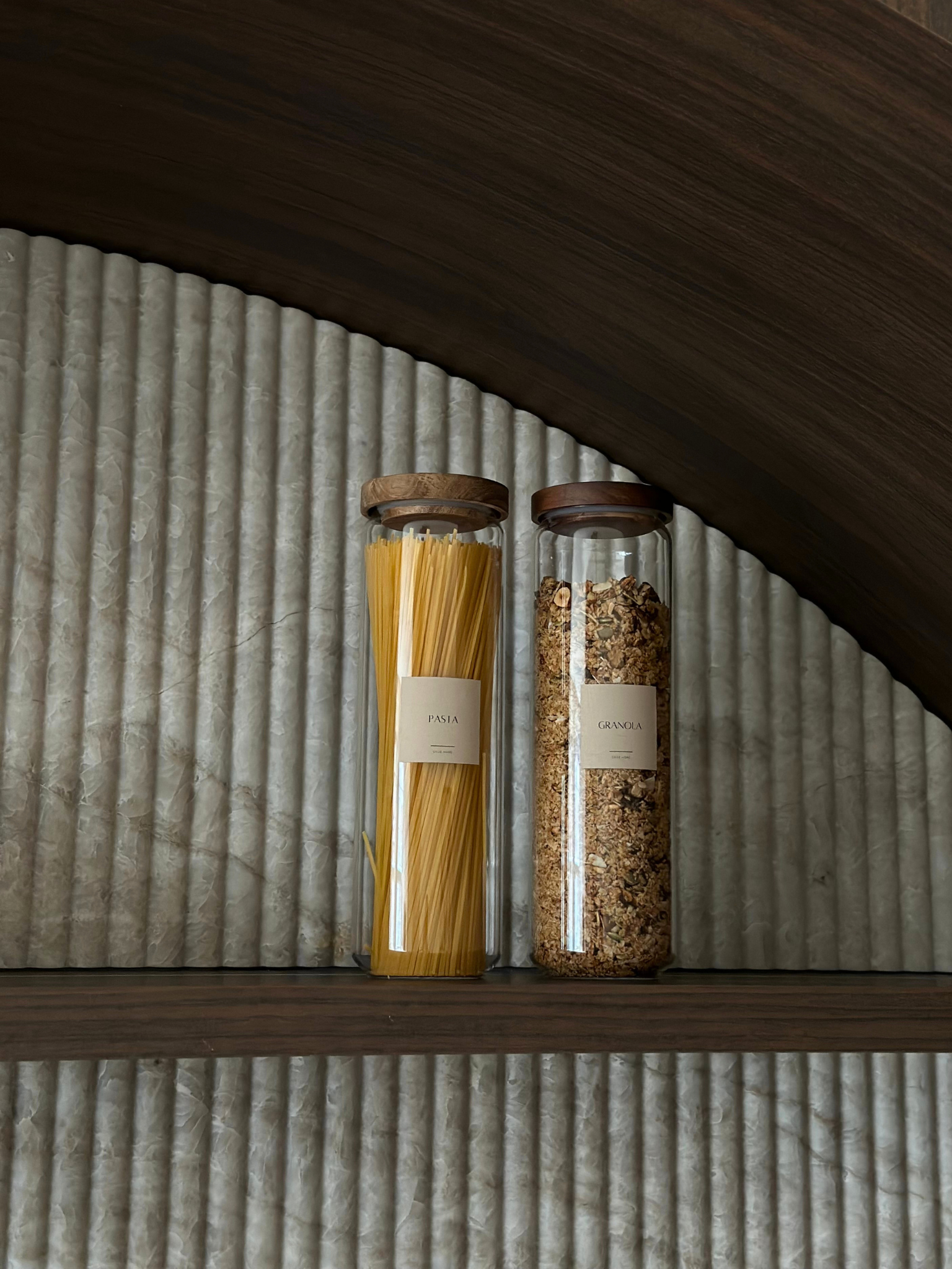 Bocal de rangement hermétique en verre Nour avec couvercle en bois d’acacia brun foncé pour une organisation élégante de la cuisine et du garde-manger, fabriqué à partir de matériaux sans toxines, sans PFAS et sans BPA, parfait pour conserver pâtes, riz, café, snacks et aliments secs de manière organisée et raffinée, avec un design transparent en verre et un couvercle épais en bois d’acacia naturel, disponible en quatre tailles différentes pour une décoration de cuisine moderne et un rangement minimaliste.