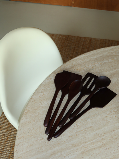 Handgemaakte houten keukengerei set van zes lepels en spatels in een diepe donkerbruine houtkleur, ideaal voor dagelijks koken, mengen, roeren, omdraaien en serveren. Gemaakt van duurzaam, SVLK-gecertificeerd hout uit Indonesië en geschikt voor contact met voedsel. Een natuurlijke, niet-toxische en plasticvrije keuze voor een bewuste keuken. Het tijdloze design past prachtig in moderne, Scandinavische, landelijke en rustieke keukens en geeft je kookruimte een warme, stijlvolle uitstraling.

