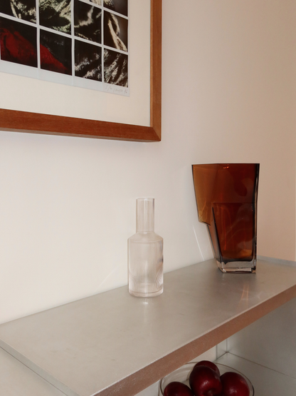 Kan Neko, eine elegante Wasser- oder Saftkaraffe mit einer dezenten Rillenstruktur, die Licht und Schatten wunderschön einfängt. Perfekt, um Wasser, Saft oder andere erfrischende Getränke stilvoll zu servieren. Hergestellt aus langlebigem, klarem Borosilikatglas – robust und hitzebeständig – mit einer handlichen Form, die sich leicht füllen und ausgießen lässt. Die Rillenstruktur verleiht einen einzigartigen, verspielten Touch, ohne zu dominieren. Kombiniere Neko mit passenden Gläsern (separat erhältlich) f