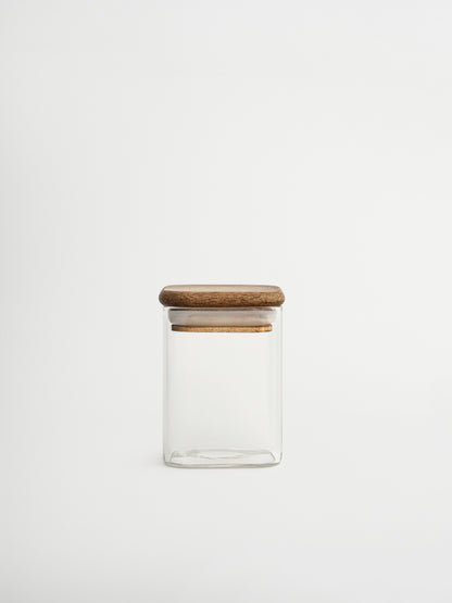 Halten Sie Ihre Kräuter ordentlich und übersichtlich mit dem Gewürzglas Kai. Dank des cleveren quadratischen Formats behalten Sie sofort den Überblick über Ihre Gewürze, was das Kochen schneller und einfacher macht. Das durchsichtige Glasgefäß besteht aus robustem Glas und ist mit einem quadratischen Akazienholzdeckel mit Gummidichtung ausgestattet, der die Kräuter lange frisch hält. Zeitlos, praktisch und gestaltet, um Ihrer Küche eine frische, stilvolle Ausstrahlung zu verleihen. Ideal kombinierbar mit pe