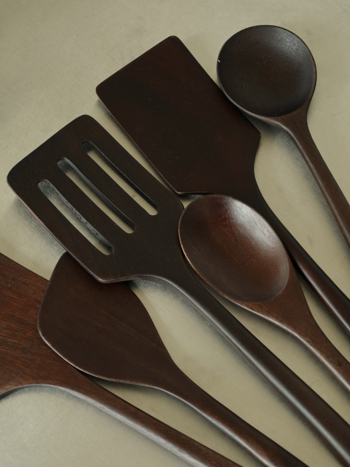 Handcrafted wooden kitchen utensil set in a rich dark brown finish, including six spoons and spatulas for everyday cooking, mixing, stirring, turning and serving. Made from durable SVLK-certified wood sourced from Indonesia and suitable for food contact. A natural, non-toxic and plastic-free choice for a more conscious kitchen. The timeless design complements modern, Scandinavian, rustic and farmhouse kitchens while adding a warm, refined touch to your cooking space.
