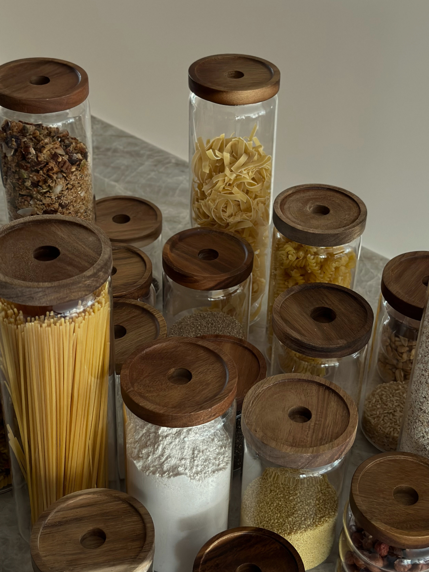 Luchtdichte glazen voorraadpot Nour met donkerbruine acaciahouten deksel voor stijlvolle keuken- en voorraadkast organisatie, gemaakt van gifvrije, PFAS-vrije en BPA-vrije materialen, perfect voor het bewaren van pasta, rijst, koffie, snacks en droge voedingsmiddelen op een elegante en georganiseerde manier, met een doorzichtige glazen pot en stevige natuurlijke acaciahouten deksel en verkrijgbaar in vier verschillende maten voor moderne keuken styling en minimalistische voorraadopslag.