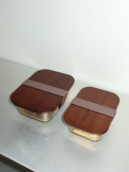 Organized storage in style with Tamar, made from amber-colored glass and finished with a wooden lid. Functional and stylish, ideal for anyone who wants to store, reheat, and organize consciously. Available in three sizes: the smallest size is perfect for yogurt, nuts, or a snack. The glass bowl (without the lid) is oven-safe, allowing you to reheat meals directly. PFAS-free, toxin-free material without BPA. Borosilicate glass.