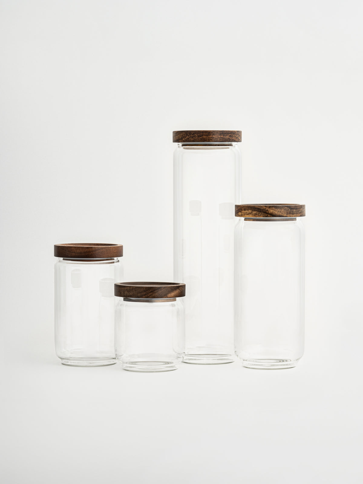 Airtight glass pantry jar Nour with dark brown acacia wood lid for elegant kitchen and pantry organization, made from toxin-free, PFAS-free and BPA-free materials, perfect for storing pasta, rice, coffee, snacks and dry foods in a stylish and organized way, featuring a transparent glass canister design with a thick natural acacia wooden lid and available in four different sizes for modern countertop styling and minimalist kitchen storage.