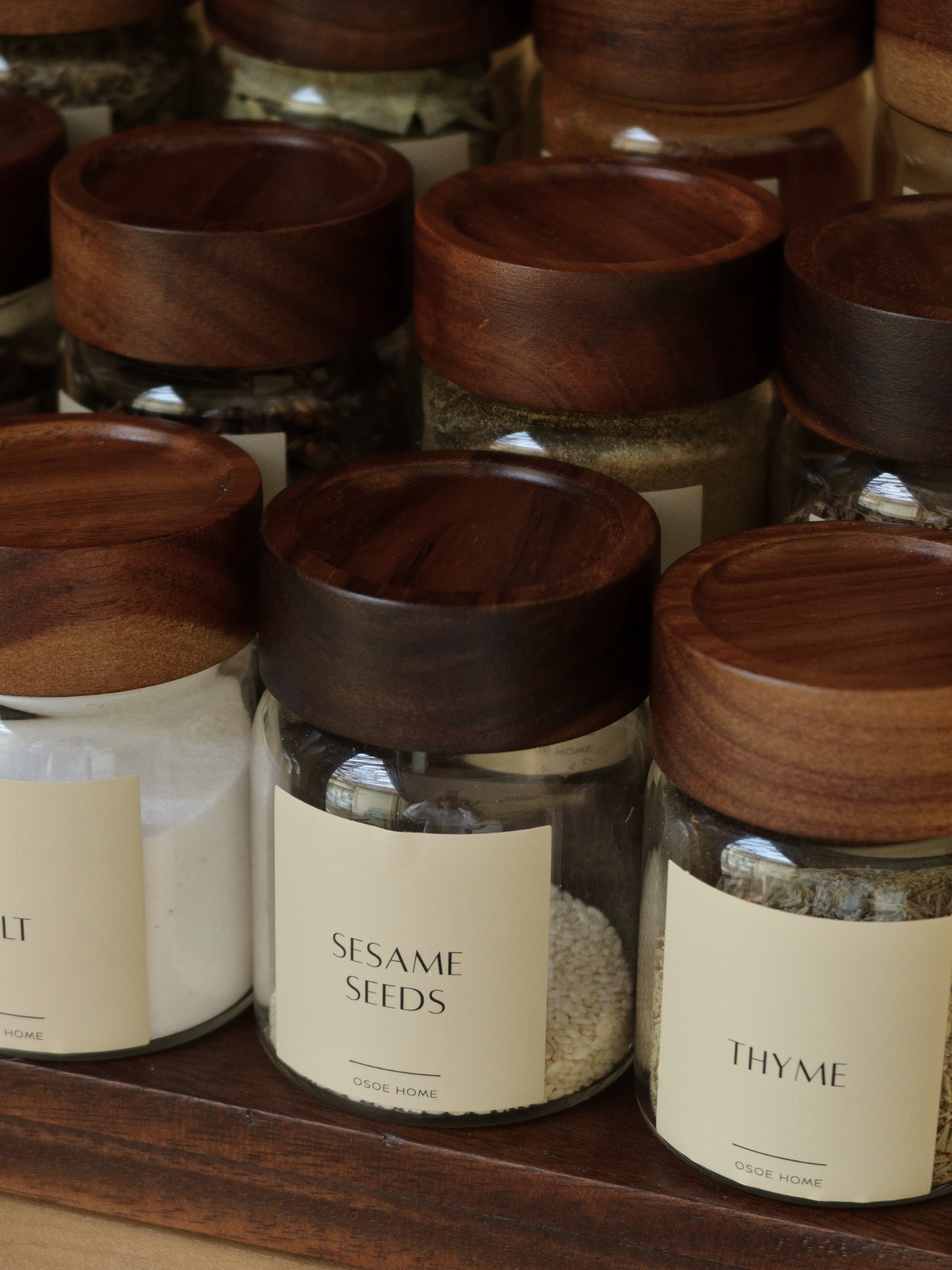 Round glass spice jar Ohm with screw cap, sprinkle lid and dark brown acacia wooden lid for organized kitchen and spice storage, made from food-safe glass and toxin-free, BPA-free and PFAS-free materials, featuring an airtight design that keeps herbs and spices fresh for longer while allowing easy seasoning during cooking, perfect for stylish spice rack organization, modern pantry storage and minimalist kitchen countertop styling.