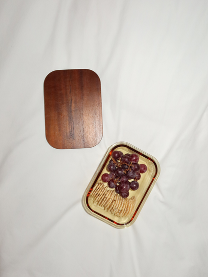 Rangez avec style grâce à Tamar, fabriqué en verre ambré et doté d’un couvercle en bois. Fonctionnel et élégant, idéal pour celles et ceux qui souhaitent conserver, réchauffer et organiser de manière consciente. Disponible en trois tailles : le plus petit format est parfait pour le yaourt, les noix ou une collation. Le bol en verre (sans couvercle) est compatible avec le four, ce qui permet de réchauffer vos plats directement. Sans PFAS, sans toxines et sans BPA. Verre borosilicate.