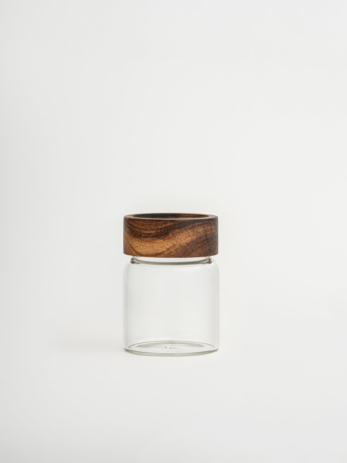 Round glass spice jar Ohm with screw cap, sprinkle lid and dark brown acacia wooden lid for organized kitchen and spice storage, made from food-safe glass and toxin-free, BPA-free and PFAS-free materials, featuring an airtight design that keeps herbs and spices fresh for longer while allowing easy seasoning during cooking, perfect for stylish spice rack organization, modern pantry storage and minimalist kitchen countertop styling.