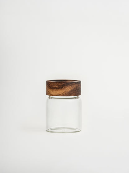 Round glass spice jar Ohm with screw cap, sprinkle lid and dark brown acacia wooden lid for organized kitchen and spice storage, made from food-safe glass and toxin-free, BPA-free and PFAS-free materials, featuring an airtight design that keeps herbs and spices fresh for longer while allowing easy seasoning during cooking, perfect for stylish spice rack organization, modern pantry storage and minimalist kitchen countertop styling.