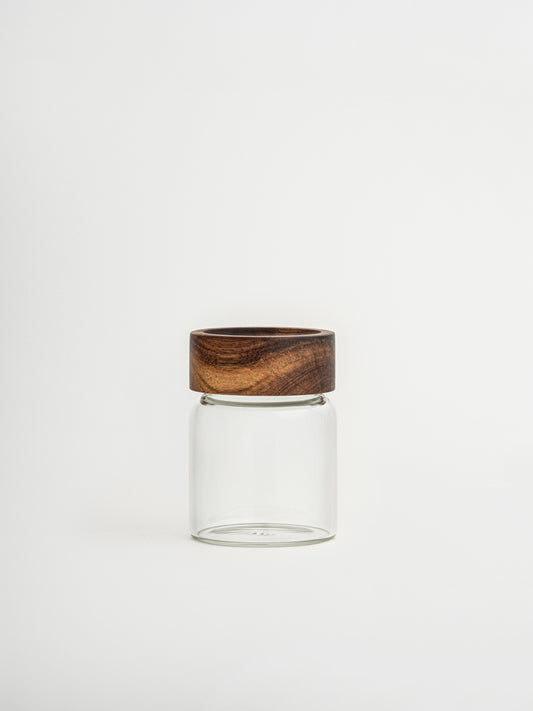 Round glass spice jar Ohm with screw cap, sprinkle lid and dark brown acacia wooden lid for organized kitchen and spice storage, made from food-safe glass and toxin-free, BPA-free and PFAS-free materials, featuring an airtight design that keeps herbs and spices fresh for longer while allowing easy seasoning during cooking, perfect for stylish spice rack organization, modern pantry storage and minimalist kitchen countertop styling.