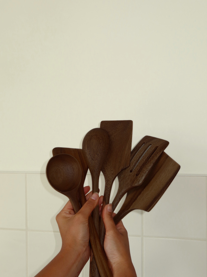 Set d’ustensiles de cuisine en bois fabriqué à la main dans une teinte brun foncé profonde, composé de six cuillères et spatules pour cuisiner, mélanger, remuer, retourner et servir au quotidien. Fabriqué en bois durable certifié SVLK provenant d’Indonésie et adapté au contact alimentaire. Un choix naturel, non toxique et sans plastique pour une cuisine plus responsable. Son design intemporel s’intègre parfaitement aux cuisines modernes, scandinaves, rustiques et de style campagne.
