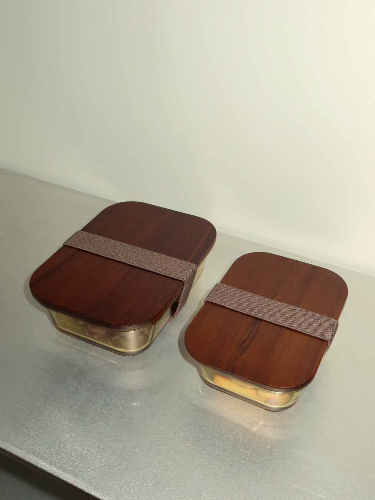 Toxin-free glass lunchbox Tamar with a natural wooden lid, designed for mindful and organized food storage. Perfect for meal prep, lunches, snacks, yoghurt, nuts and leftovers. Available in three sizes to suit every meal and everyday need. The glass container without the lid is oven-safe, allowing you to heat meals directly in the same dish. A matching elastic band keeps the wooden lid securely in place. A stylish, plastic-free alternative to traditional lunchboxes and food storage containers.