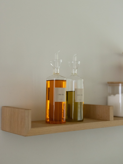 Transparenter Öl- und Essigspender Vivi, ein stilvolles Set aus zwei Glasflaschen für Öl, Essig und andere flüssige Würzmittel. Das klare Design macht den Inhalt leicht erkennbar und sorgt für eine aufgeräumte, minimalistische Optik in der Küche oder auf dem Esstisch. Ideal für Olivenöl, Balsamico, Dressings und Saucen – zum Kochen oder Servieren. Passende „Oil“- und „Vinegar“-Etiketten sind separat erhältlich und sorgen für noch mehr Ordnung.