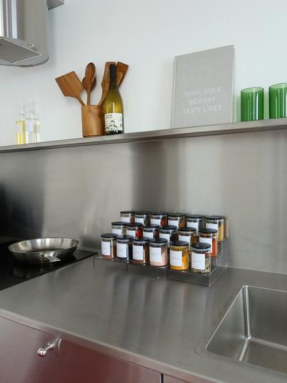 Uitschuifbaar kruidenrek van doorzichtig acryl, ontworpen om kruidenpotjes overzichtelijk op te bergen in een keukenlade. Dit transparante opbergsysteem zorgt voor een strak, minimalistisch en georganiseerd geheel, waarbij alle kruidenpotjes goed zichtbaar en makkelijk bereikbaar zijn. Een ruimtebesparend kruiden organizer en lade organizer die verstelbaar is voor verschillende lade-afmetingen en bijdraagt aan een overzichtelijke keukenorganisatie. Ideaal voor het netjes opbergen van kruidenpotjes.