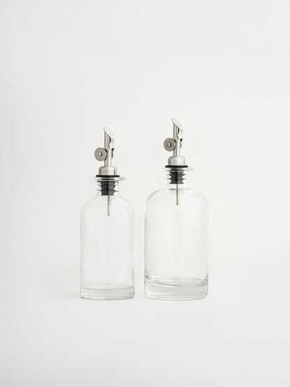 oliedispenser zilveren dop, azijndispenser zilveren schenktuit, glazen fles voor olie en azijn, dispenser in twee maten, olijfoliefles, azijnfles keuken, glazen oliedispenser, keukenaccessoire olie, zilveren schenktuit, keuken organizer fles, moderne keukenfles, luchtdichte oliefles, nauwkeurig schenken, stijlvolle dispenser, glazen voorraadfles, olie en azijn set, zilveren keukenaccessoire