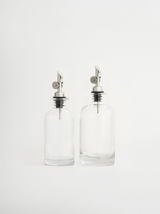 oliedispenser zilveren dop, azijndispenser zilveren schenktuit, glazen fles voor olie en azijn, dispenser in twee maten, olijfoliefles, azijnfles keuken, glazen oliedispenser, keukenaccessoire olie, zilveren schenktuit, keuken organizer fles, moderne keukenfles, luchtdichte oliefles, nauwkeurig schenken, stijlvolle dispenser, glazen voorraadfles, olie en azijn set, zilveren keukenaccessoire
