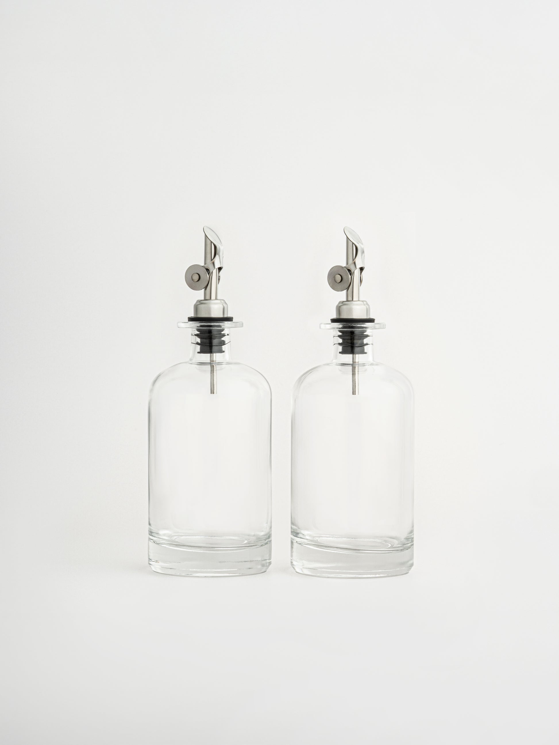 oil dispenser silver cap, vinegar dispenser silver spout, glass oil bottle, glass vinegar bottle, dispenser in two sizes, olive oil bottle, airtight oil container, silver pouring spout, non-drip oil dispenser, kitchen organizer bottle, elegant glass dispenser, modern kitchen accessory, pour control spout, oil and vinegar set, storage bottle for kitchen